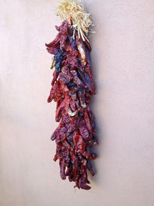 Red chili peppers bundled and hanging to dry, by SteveStrummer (Own work) [CC0], via Wikimedia Commons